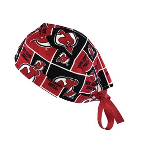 May include: Red and black scrub hat with a checkered pattern featuring the New Jersey Devils logo and team name.