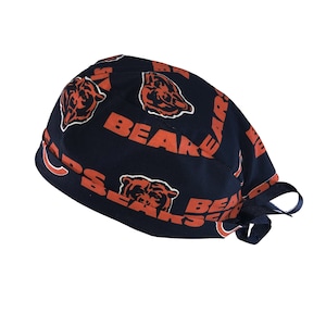May include: A navy blue surgical scrub hat with a repeating pattern of orange bear heads and the word "Bears".