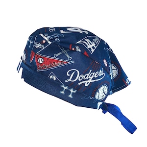 May include: A blue and white baseball-themed bandana with the words "Los Angeles Dodgers" printed on it. The bandana has a red and white pennant with the words "Los Angeles Dodgers" printed on it. The bandana has a tie string.