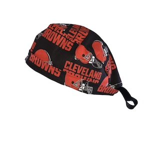 May include: A black scrub cap featuring a repeating pattern of orange Cleveland Browns football helmets and the team name in orange block letters. The cap has a black elastic band.