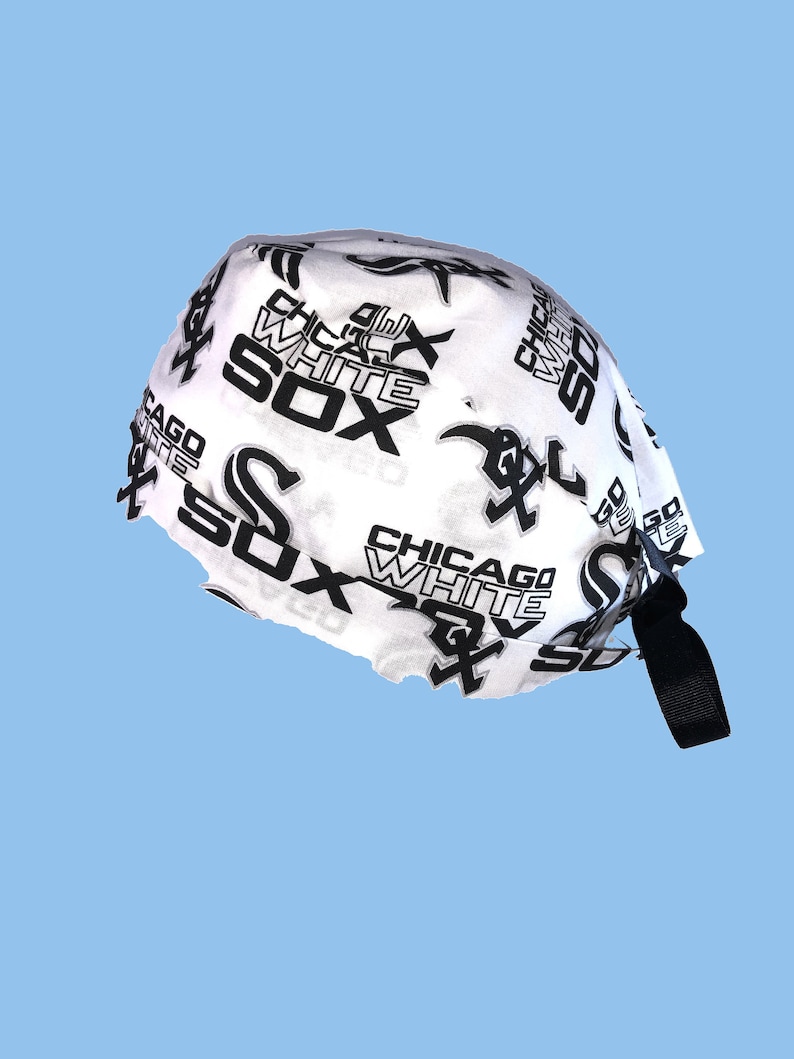 May include: White baseball cap with a black and white print of the Chicago White Sox logo. The cap has a black adjustable strap.