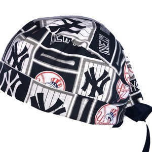 May include: A black and white surgical scrub hat with a New York Yankees theme. The hat features the team's logo, baseballs, and the words "New York" and "Yankees".