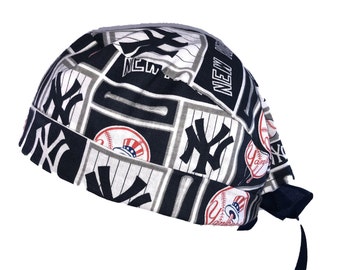 May include: A black and white surgical scrub hat with a New York Yankees theme. The hat features the team's logo, baseballs, and the words "New York" and "Yankees".