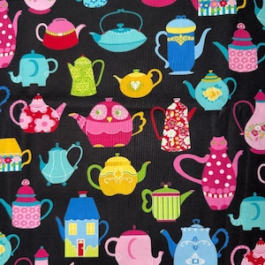 May include: A black fabric featuring a repeating pattern of colorful teapots in various shapes and designs, including pink, blue, yellow, and green hues. The teapots display diverse motifs such as floral prints, polka dots, and animal-like silhouettes.
