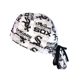 May include: White surgical scrub hat with a black and white print of the Chicago White Sox logo and team name. The hat has a black tie.