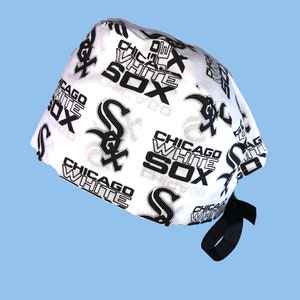 May include: White and black patterned surgical scrub hat with a black tie. The pattern features the Chicago White Sox logo and text.