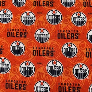 May include: Orange fabric featuring a repeating pattern of the Edmonton Oilers logo. The logo is a white circle with a black and orange design, and the word "OILERS" is printed in black. The fabric also has the words "EDMONTON OILERS" in black.