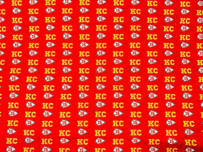 May include: Red fabric with a repeating pattern of yellow "KC 15" logos. The logos are in a stylised font with a small arrow pointing to the right.