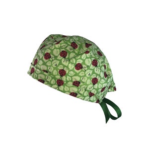 May include: Green surgical scrub hat with a pattern of red ladybugs on green leaves. The hat has a green tie.
