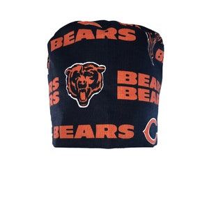 May include: A black scrub hat with an orange and white Chicago Bears logo pattern. The hat has the words "BEARS" printed on it.