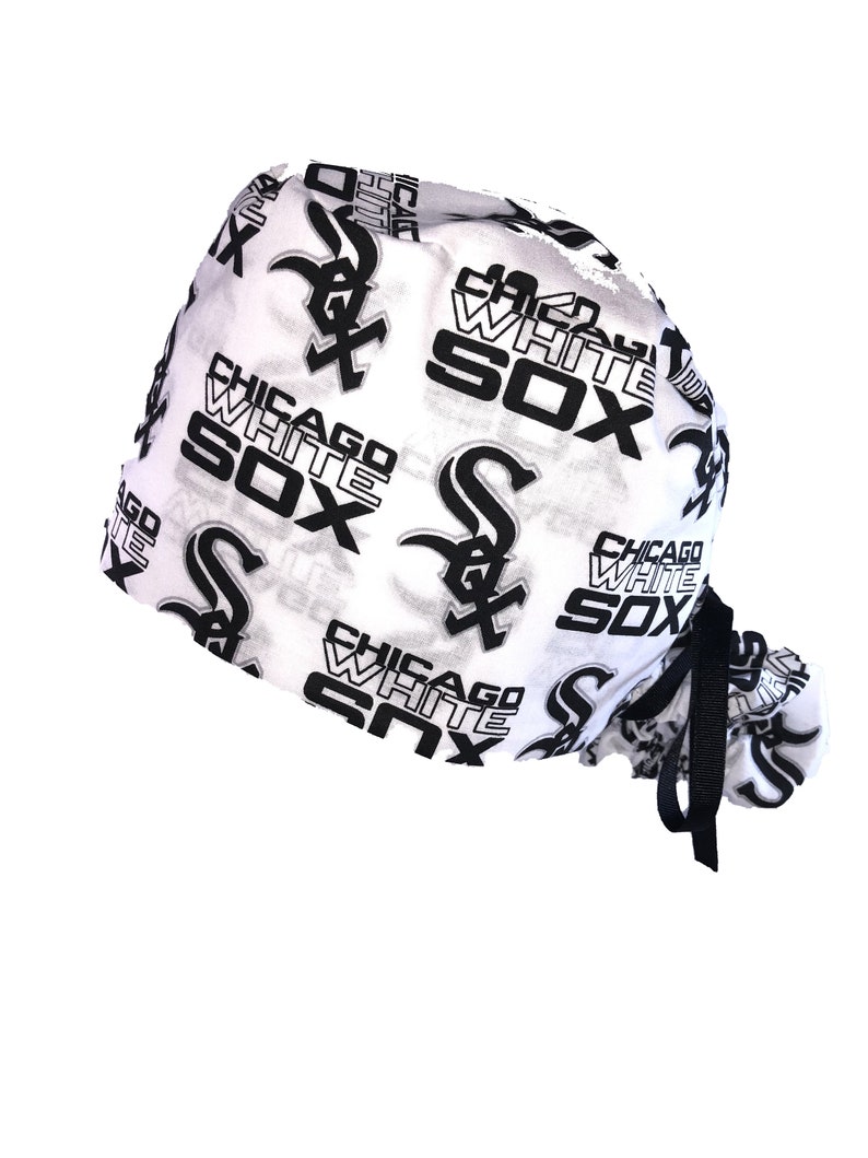 May include: White surgical scrub hat with a black and white print of the Chicago White Sox logo and text. The hat has a black drawstring.