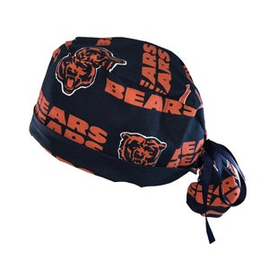 May include: A blue and orange surgical scrub hat with a repeated pattern of the Chicago Bears logo and the word "Bears".