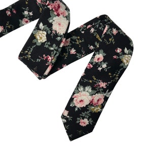 May include: A black necktie with a floral pattern featuring pink and white flowers on a black background.