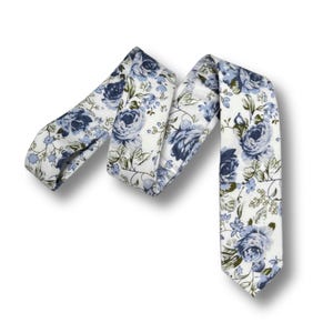 May include: A floral tie featuring a pattern of blue roses and green leaves on a white background. The tie is made of fabric and is designed for formal or semi-formal wear. The tie is a classic accessory.