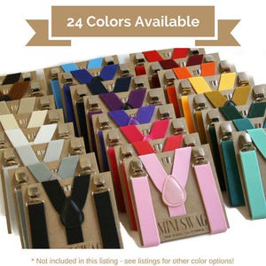 May include: A display of clip-on suspenders in various colors, including black, pink, and blue. Each pair is attached to a cardboard backing with silver-toned clips. The text "24 Colors Available" is at the top.