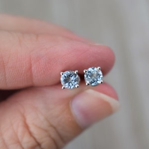 May include: A pair of silver stud earrings with light blue round gemstones.