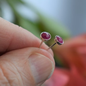 May include: A pair of silver stud earrings with small, round, pink gemstones.