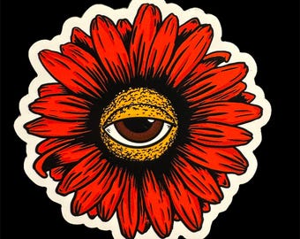 May include: A red flower with a large eye in the center. The eye is brown with a yellow iris and a black pupil.