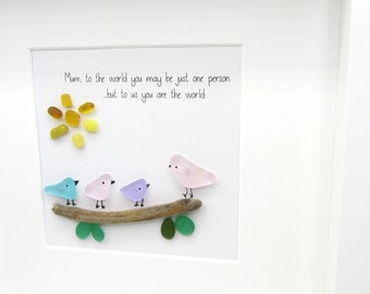 Puede incluir: Una obra de arte enmarcada con fondo blanco y una cita que dice "Mamá, para el mundo puedes ser solo una persona, pero para nosotros eres el mundo". La obra presenta un sol amarillo hecho de piedras de vidrio y tres pájaros en una rama, también hechos de piedras de vidrio.