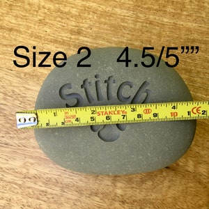 May include: A gray stone with the word "Stitch" engraved on it. The stone is 4.5 inches in diameter and is labeled "Size 2".
