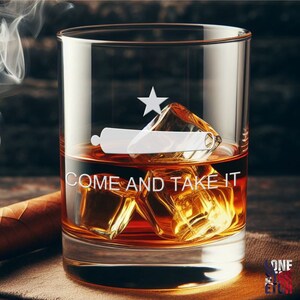 May include: A clear glass whiskey tumbler with a white etched design of the Texas flag and the words "COME AND TAKE IT".