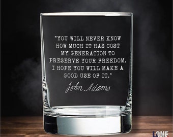 Puede incluir: Un vaso de whisky de vidrio transparente con una cita grabada de John Adams: "Nunca sabrás cuánto le ha costado a mi generación preservar tu libertad. Espero que le des un buen uso."