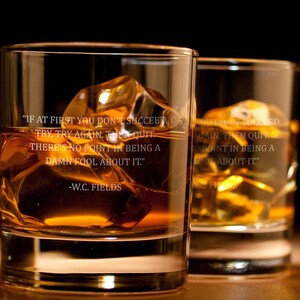 May include: Two clear glass tumblers filled with amber liquid and ice cubes. The tumblers have a quote etched on the side: "If at first you don't succeed, try, try again. Then quit. There's no point in being a damn fool about it." -W.C. Fields