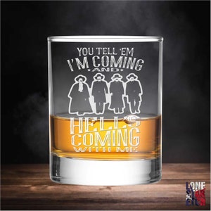 May include: A clear glass rocks glass with an etched design. The design features four figures in cowboy hats and the text "You tell 'em I'm coming and hell's coming with me".