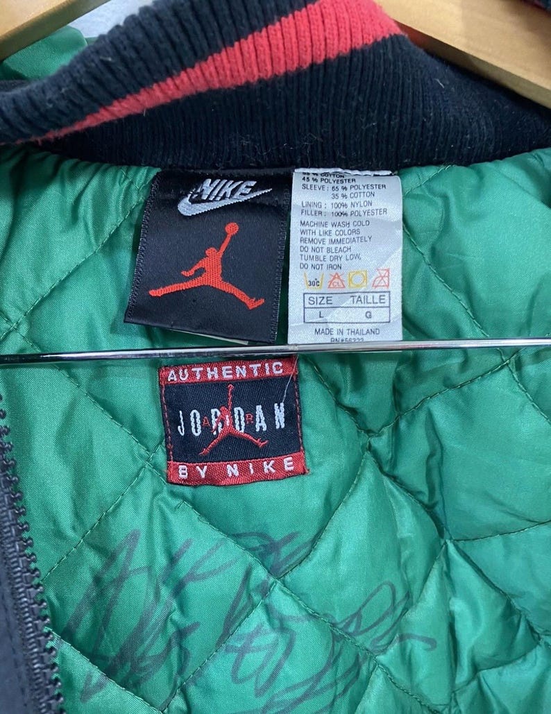 Pu&ograve; includere: Una giacca reversibile nera e verde con un colletto rosso e nero. La giacca ha una chiusura a zip e una grande toppa "Authentic Jordan by Nike" sul davanti. La fodera &egrave; verde e ha un motivo trapuntato. L'etichetta sulla giacca dice "Taglia L, Taille G, Prodotto in Thailandia".