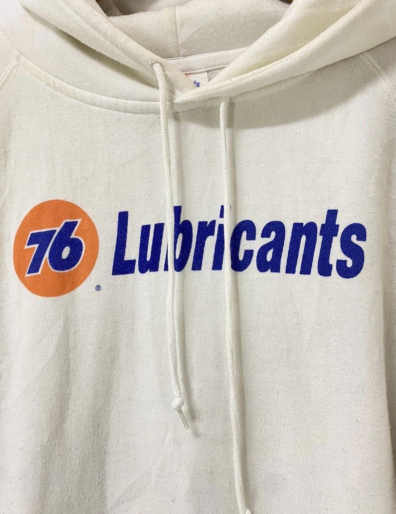 Puede incluir: Sudadera con capucha blanca con un logotipo azul y naranja que dice "76 Lubricants".