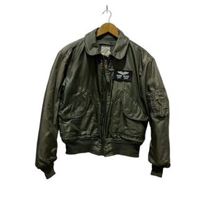 May include: A green bomber jacket with a zip fastening and a patch that reads "GEORGE WALKER CAPT. USAF".