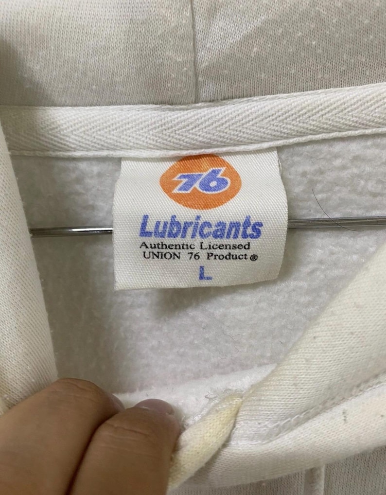 Puede incluir: Sudadera con capucha blanca con un logotipo 76 y el texto "Lubricants Authentic Licensed UNION 76 Product" en la etiqueta.