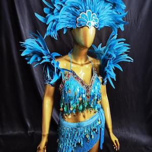 May include: A vibrant blue costume with a feathered headdress, shoulder pieces, and a halter top adorned with sequins and coins. The costume includes a fringed skirt, creating a festive and eye-catching ensemble.