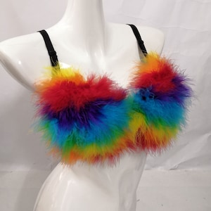 May include: A rainbow feather bra with black straps. The bra is made of soft, colourful feathers and is perfect for a festival or party.