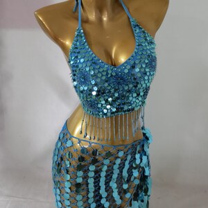 May include: A turquoise blue sequined belly dancing costume with a halter top and a skirt with fringe. The top and skirt are both covered in sequins and beads.