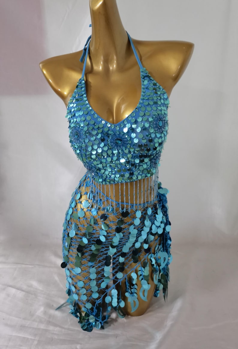 May include: A blue sequined halter top and matching skirt with fringe. The top has a V-neckline and the skirt is a wrap style.
