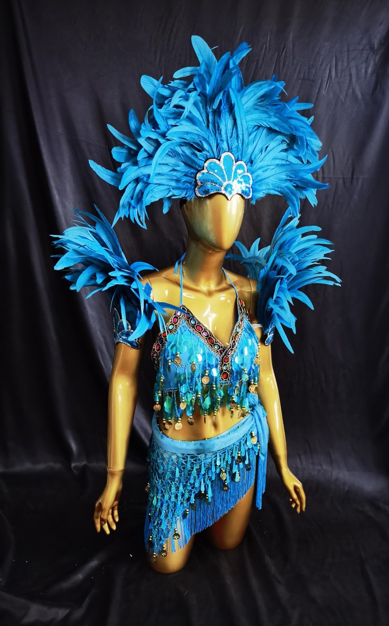 May include: A vibrant blue costume with a feathered headdress, shoulder pieces, and a halter top adorned with sequins and coins. The costume includes a fringed skirt, creating a festive and eye-catching ensemble.