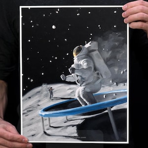 May include: Fine art print featuring an astronaut bouncing on a blue trampoline on the moon, with another astronaut in the background. The print is 11x14 inches in size. The artwork is set against a black starry sky.