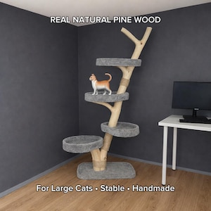 May include: A handmade cat tree made of natural pine wood. The tree features multiple gray carpeted platforms and a natural wood branch design. A small orange and white cat is standing on one of the platforms. The text reads: "For Large Cats • Stable • Handmade."