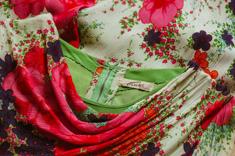 May include: A white dress with a green bodice and a pink floral print. The dress has a zipper closure and a label that reads "Bruiser."