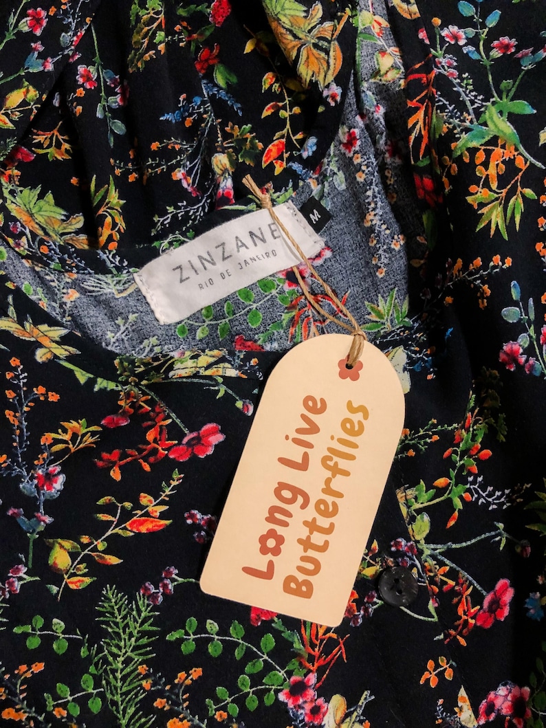 May include: Black floral print top with a tag that reads "Long Live Butterflies." The top has a round neckline and a button closure. The tag also has the text "ZINZANE RIO DE JANEIRO."