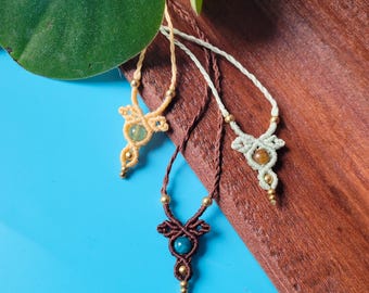 May include: Three macrame necklaces with different colored stones. The necklaces are made with brown, white, and beige cord. The stones are green, brown, and blue.