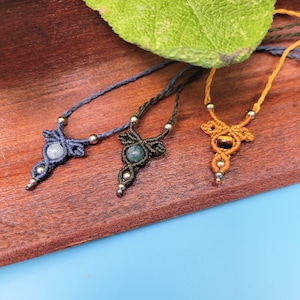 May include: Three necklaces with different colored cords and gemstone pendants. The necklaces are made with macrame knots and feature a blue, green, and tiger's eye stone.