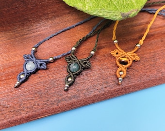 Puede incluir: Tres collares con cordones de diferentes colores y colgantes de piedras preciosas. Los collares están hechos con nudos de macramé y presentan una piedra azul, verde y ojo de tigre.
