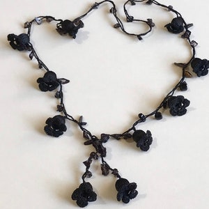 May include: Black crocheted necklace with small black flower accents.