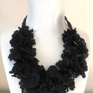 May include: A black beaded necklace with a floral design. The necklace is made of black beads and black lace.