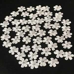 May include: A collection of white lace flower embellishments. The flowers are small and delicate, with a pearl-like centre. They are perfect for adding a touch of elegance to any craft project.