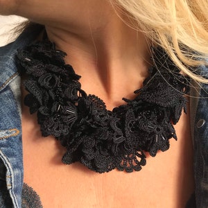 May include: A black crocheted necklace with beaded accents. The necklace is layered and has a delicate, floral design.
