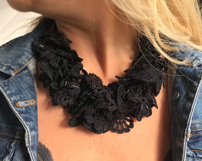 May include: A black crocheted necklace with beaded accents. The necklace is layered and has a delicate, floral design.