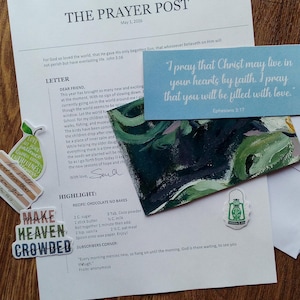 May include: A collection of stationery items including a printed letter, a card with a quote, and decorative stickers. The letter is titled "The Prayer Post" and includes a recipe for chocolate no-bakes. A small, green lantern-shaped sticker is also present.